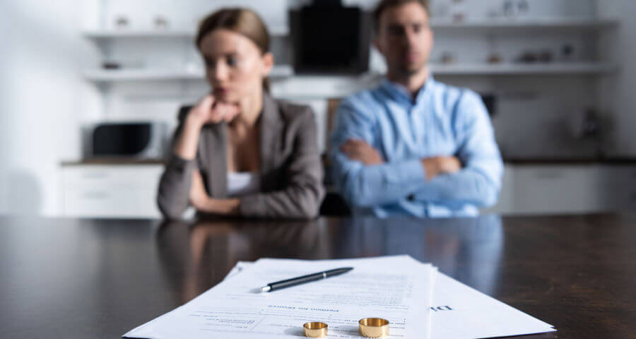 a couple sat, divorce papers & married rings, about to get a divorce.