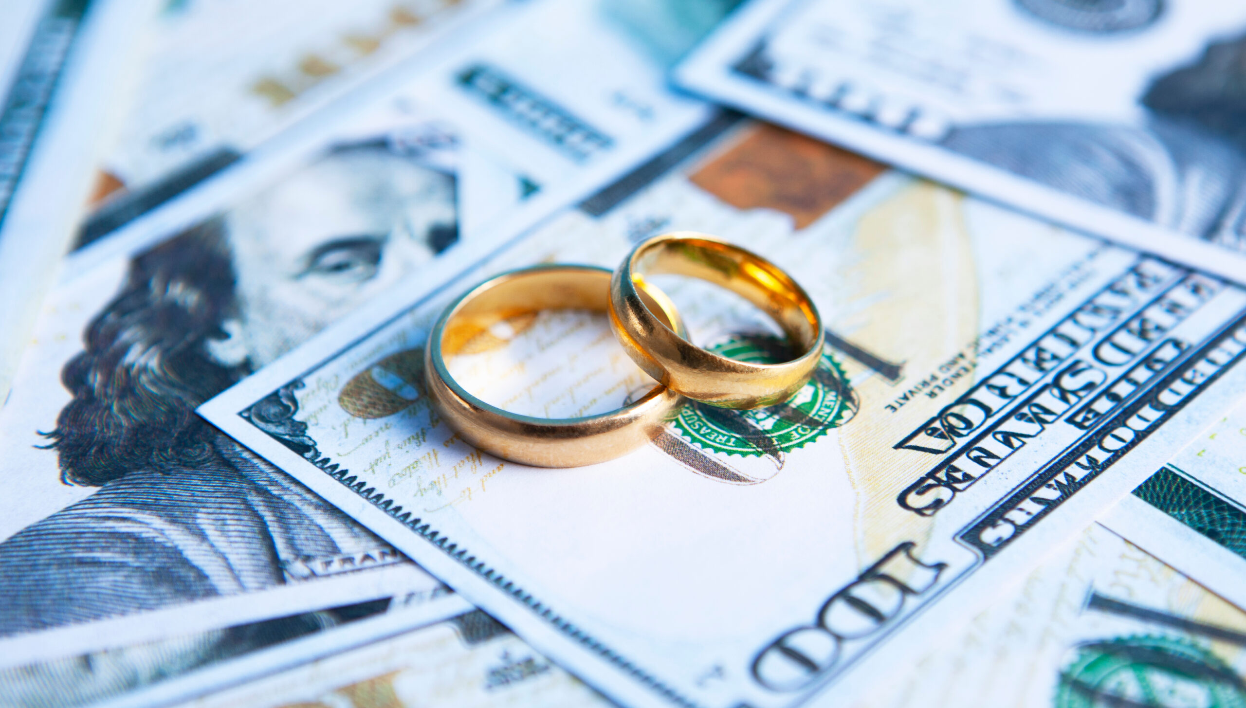 Marriage rings over dollar bills.